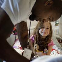 Faith Falzon of Dexter smiles, hugs a signed teddy bear and looks up at former Univeristy of Michigan football player Charles Woodson as he signs a hat for her Saturday afternoon at C.S. Mott Children's Hospital. "I have something to show you," Faith later said, motioning a thumbs down while saying "Michigan State."Jeffrey Smith | AnnArbor.com
